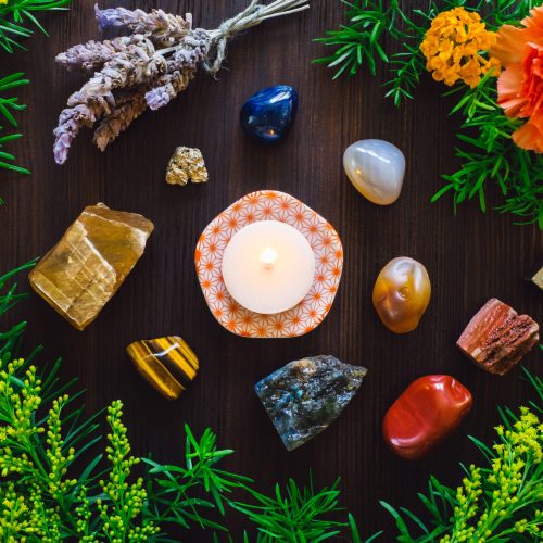 Lit Candle with Stones and Flowers of Summer, including Agate, Honey Calcite, Red Jasper, Labradorite and Pyrite