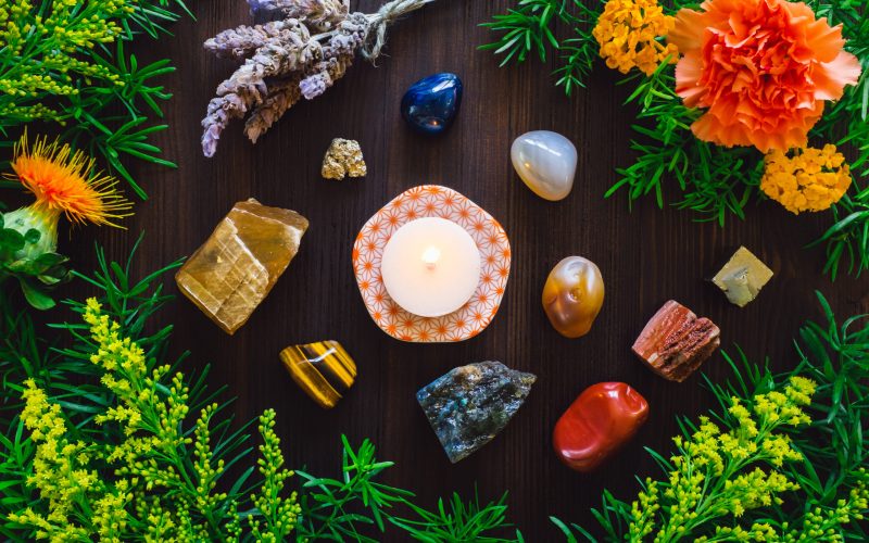 Lit Candle with Stones and Flowers of Summer, including Agate, Honey Calcite, Red Jasper, Labradorite and Pyrite