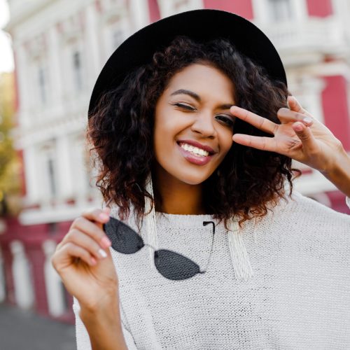 Cute black woman posing outdoor. Showing signs and smiling. Happy emotions. fashion look. Traveling girl.